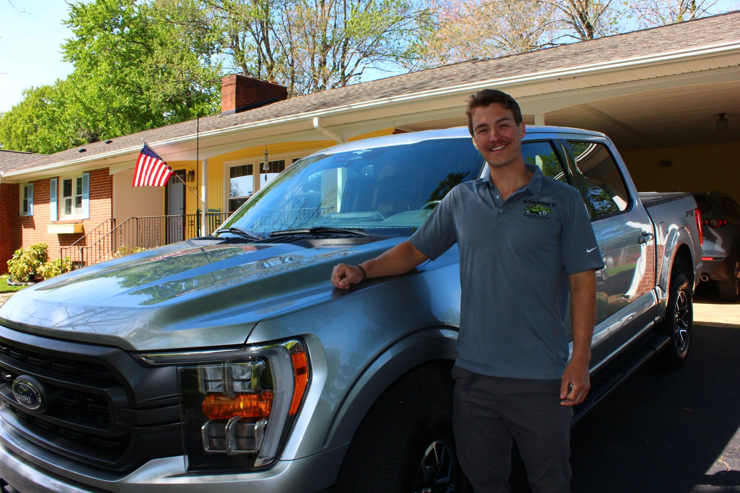 Jack Stansky in a Stansky Construction polo, leaning on his pickup truck in a driveway